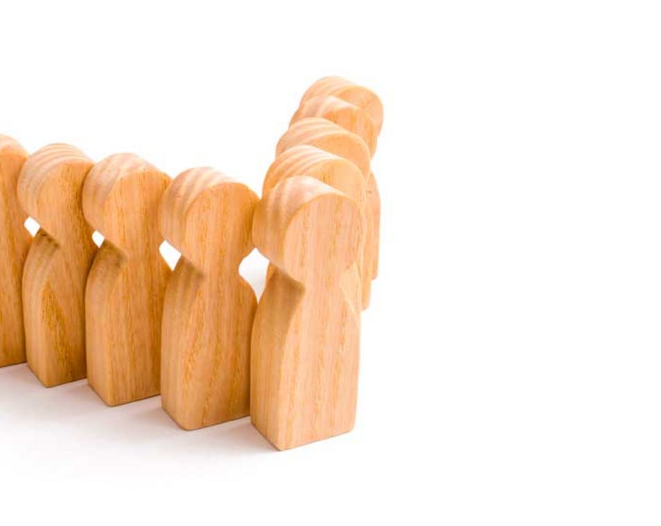 Symbolbild Teamleitung: Holzfiguren stehen in einer V-förmigen Position