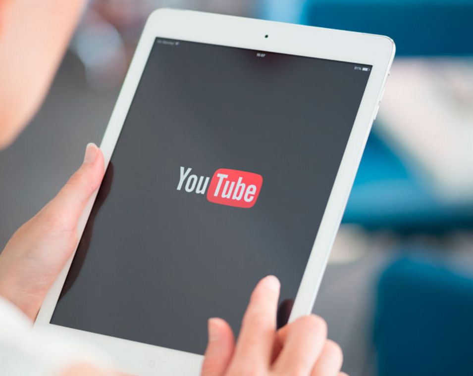 Frau hält ein Tablet mit dem Youtube-Logo auf dem Bildschirm