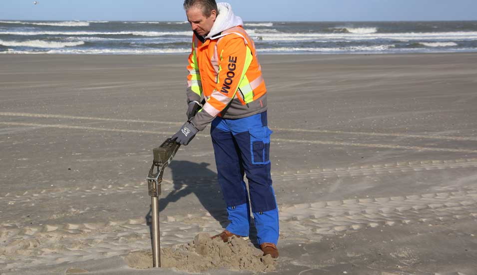 Ein Kampfmittelräumer steht auf dem Strand von Wangerooge und sucht mit Hilfe einer Sonde nach alter Munition in der Nordsee.