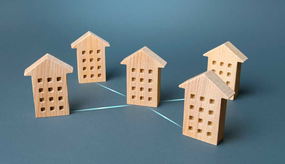 Symbolbild: fünf große Häuser aus Holz, die mit Linien verbunden sind