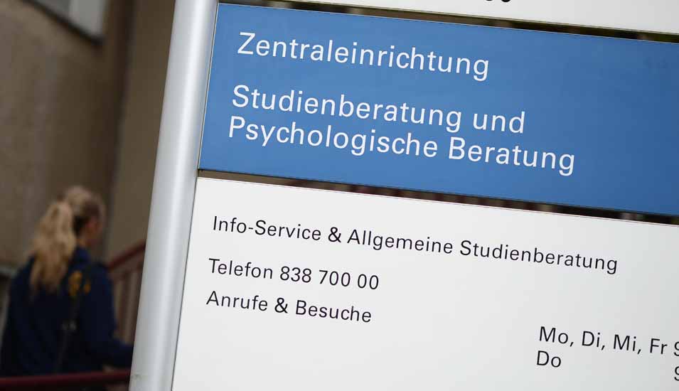 Eine Studentin läuft an einer Hinweistafel für die Studienberatung und psychologische Beratung für Studenten an der FU Berlin vorbei