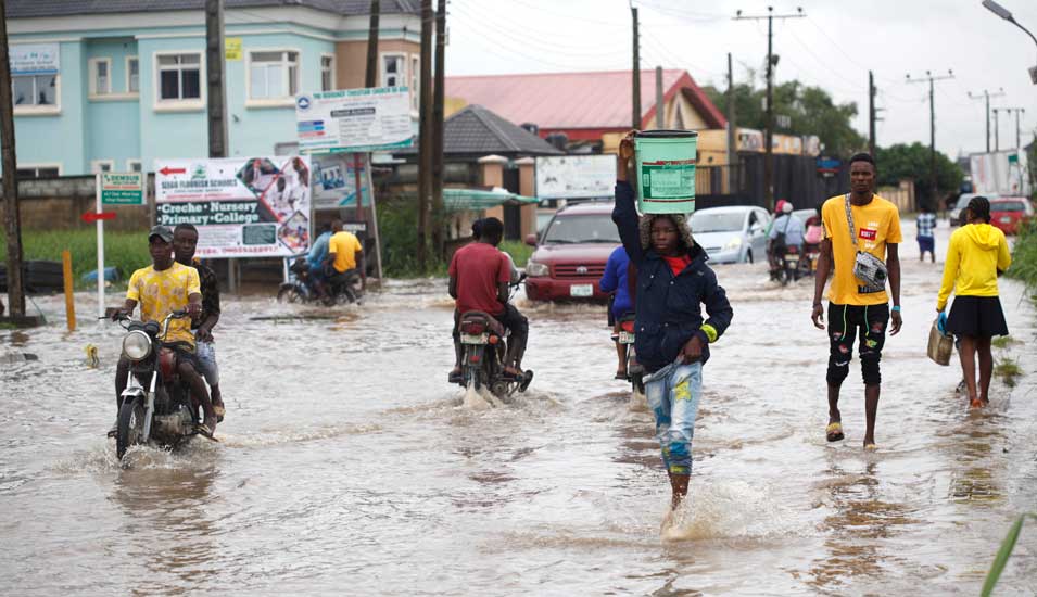Menschen laufen und fahren auf einer überschwemmten Straße in Lagos, Nigeria