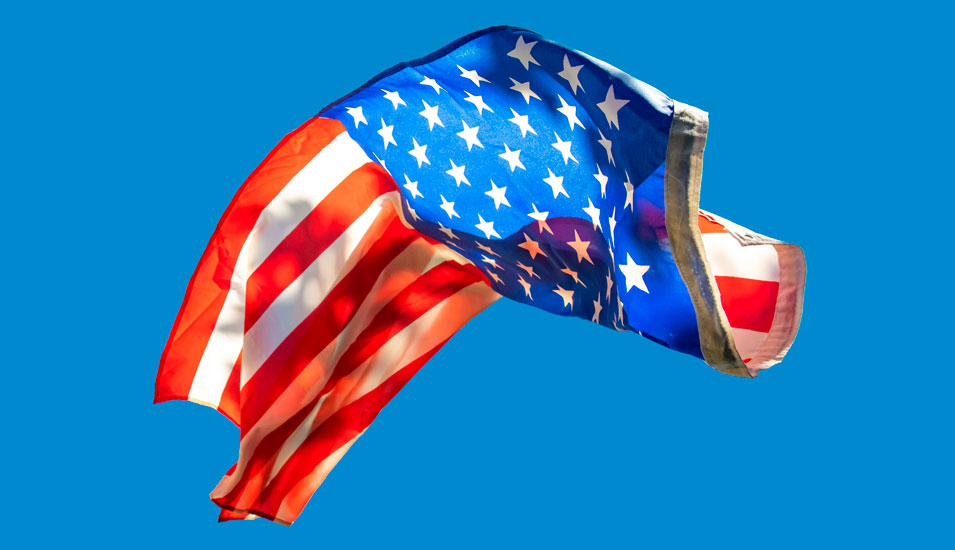 Eine fallende US-Flagge vor blauam Himmel.
