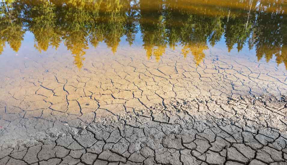 Niedriger Wasserstand und aufgerissener Boden in einem See aufgrund anhaltender Trockenheit
