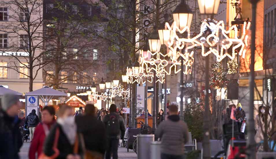 Passanten in einer Fußgängerzone mit Weihnachtsbeleuchtung in München